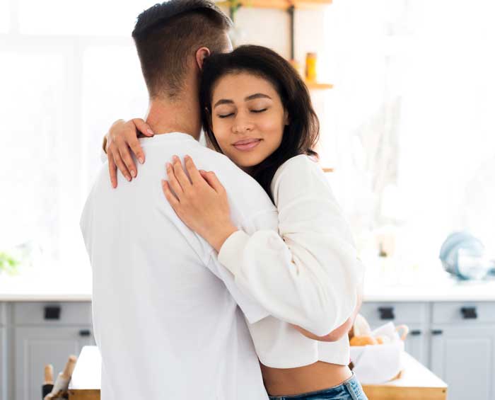 attractive ethnic young woman hugging boyfriend with closed eyes